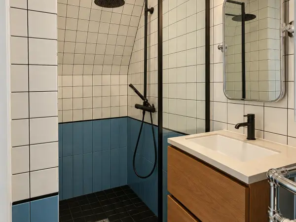 Salle de bains en suite : douche ouverte, carrelage blanc et bleu.