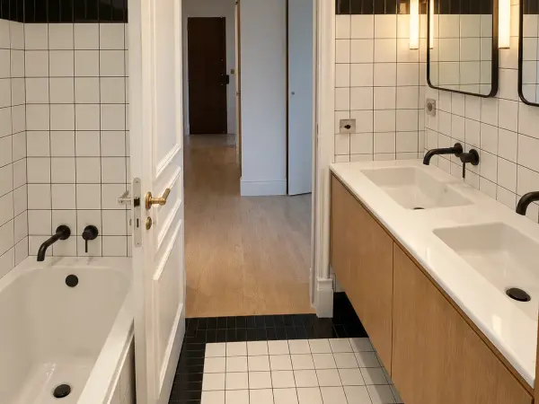 Salle de bains au carrelage blanc, double vasque sur meuble bois.