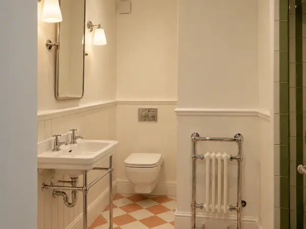 Salle de bains au sol en damier, vasque sur piètement inox.