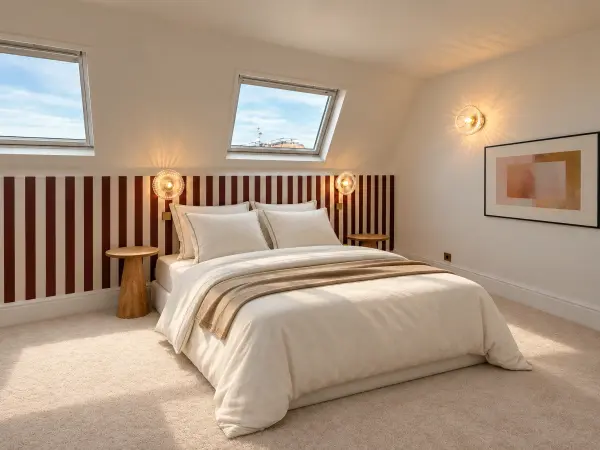 Chambre mansardée éclairée par deux fenêtres de toit.