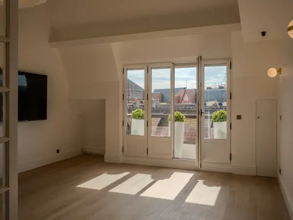 Salon du 1er niveau sous combles avec vue sur les toits environnants depuis le balcon.