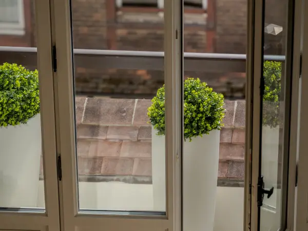 Porte-fenêtre ouvrant sur un balcon, vue sur les toits.
