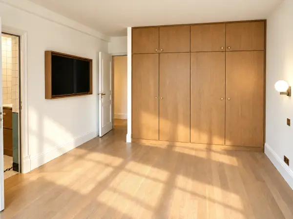 Chambre au parquet clair avec placards intégrés sur toute la largeur.