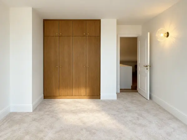 Chambre avec placard intégré fermé et vue vers le palier.