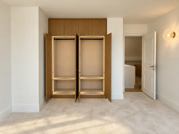 Chambre avec rangements sur mesure en chêne, vue vers le dégagement.