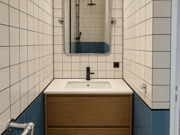 Vasque sur meuble bois sous carrelage blanc et bleu.