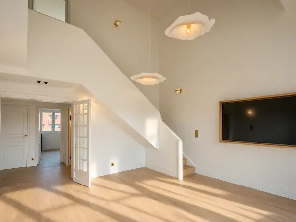 Salon du 1er niveau en double hauteur avec escalier desservant la mezzanine.