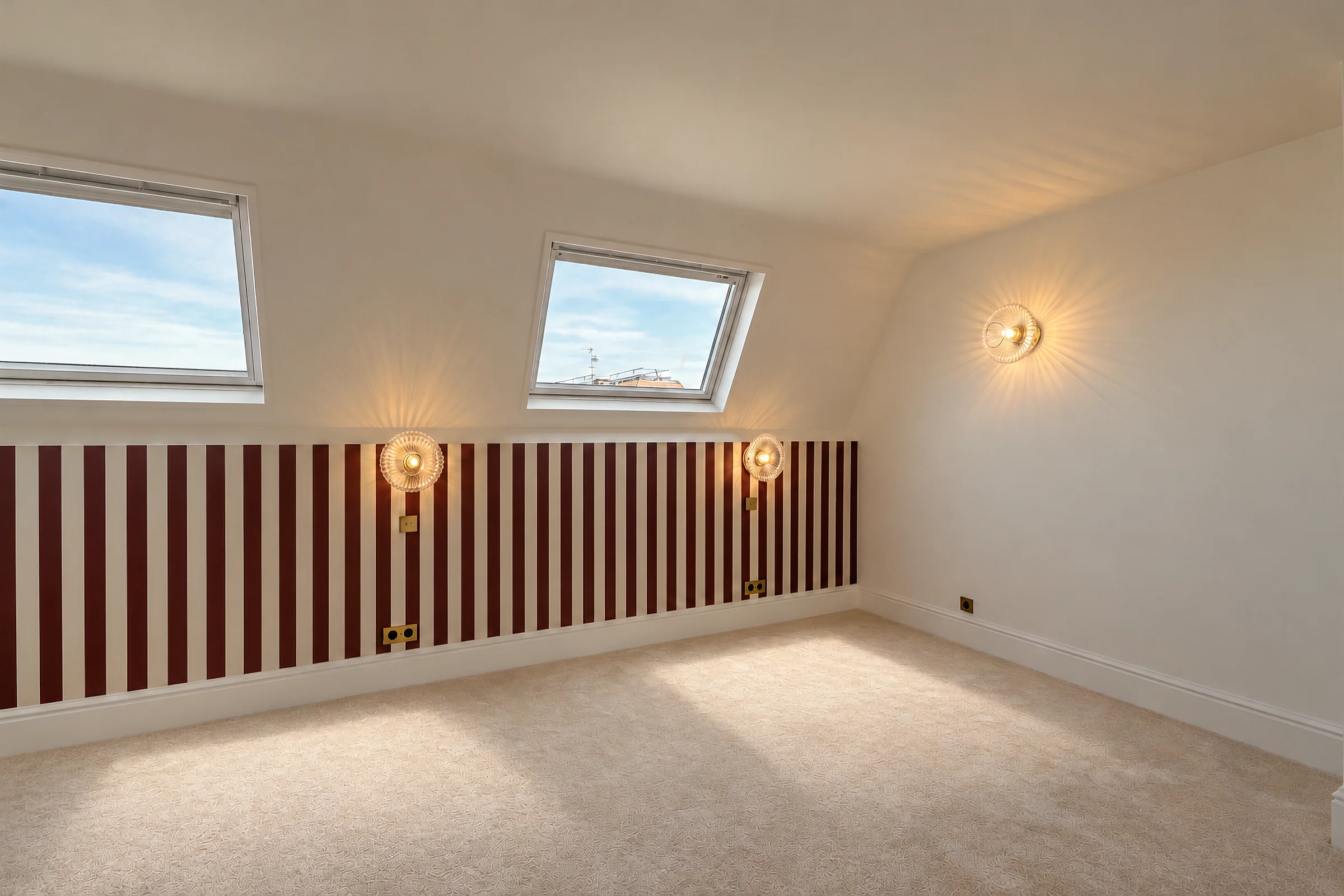 Chambre mansardée éclairée par deux fenêtres de toit.