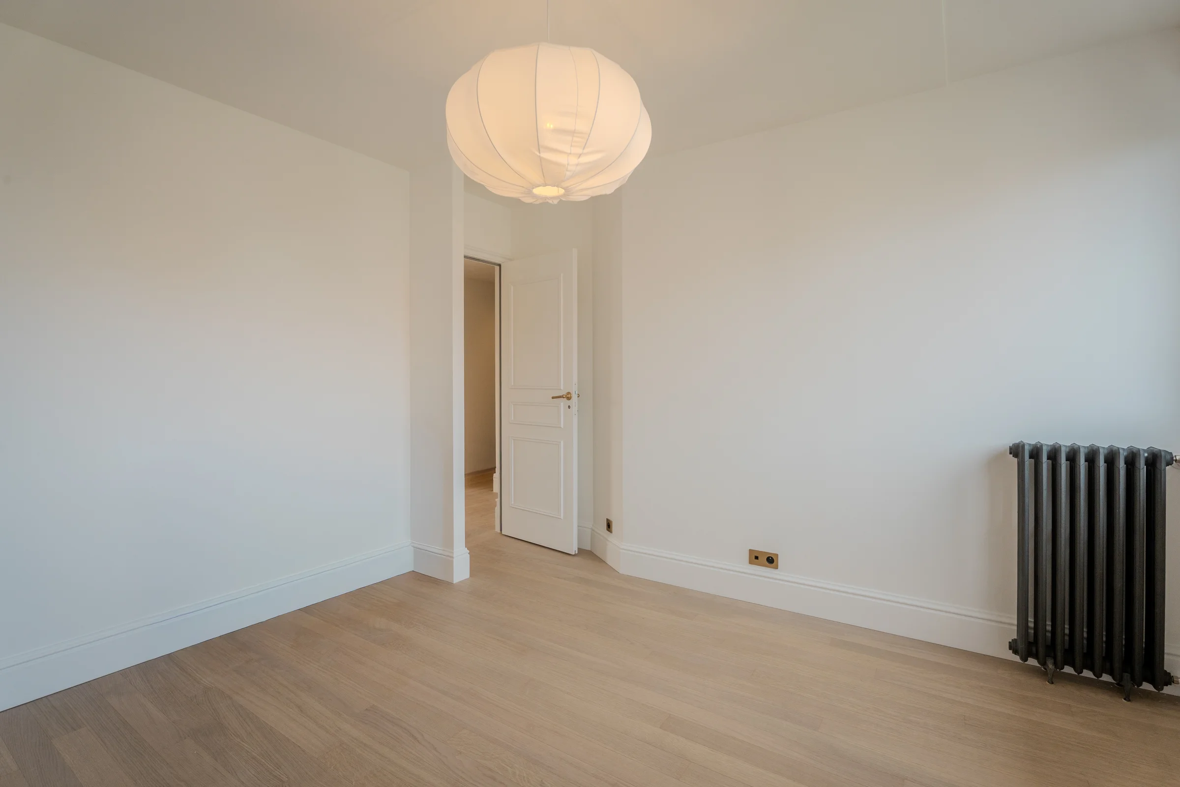 Pièce claire au parquet clair, porte ouverte sur le couloir.